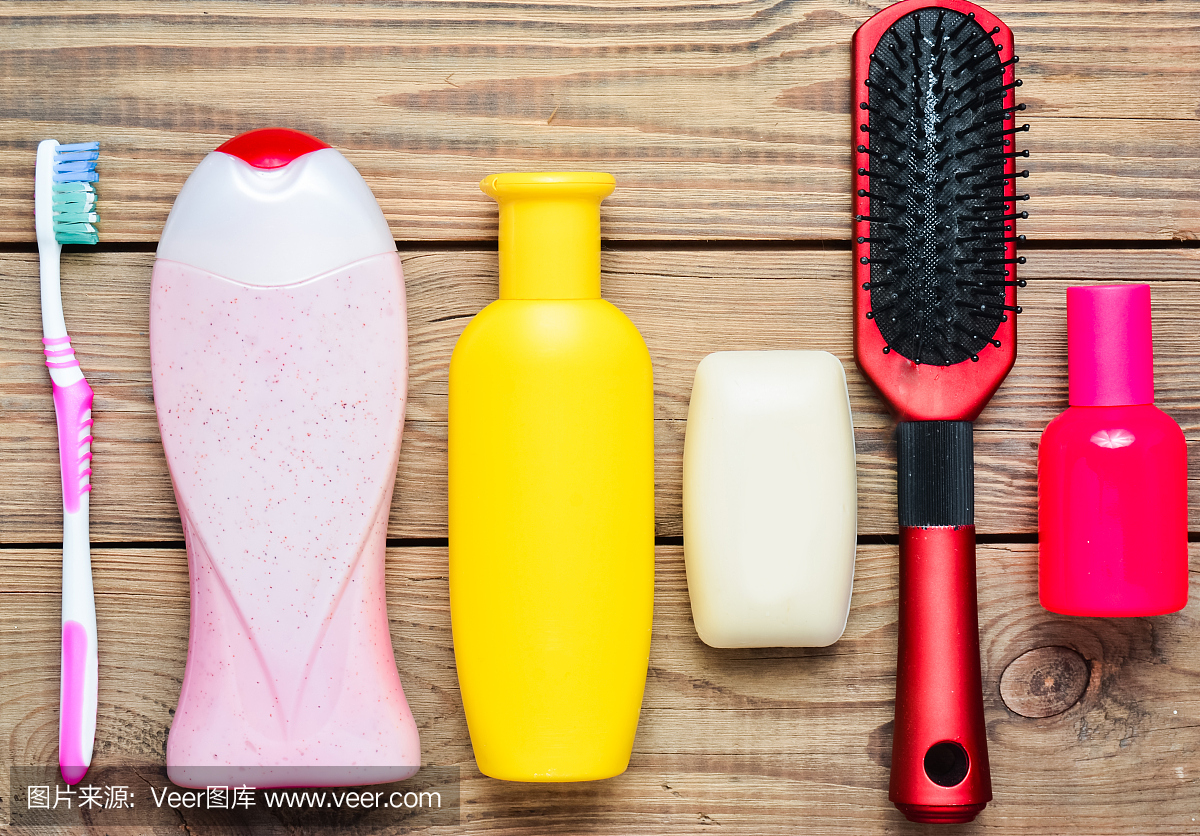 洗发精,沐浴露,肥皂,香水,牙刷,梳子。护理美容和卫生的产品。木制桌子上的俯视图